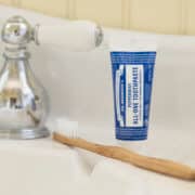 Travel-size toothpaste next to a toothbrush and bathroom sink