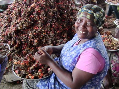 A woman posing for a photo with oil palm fruit