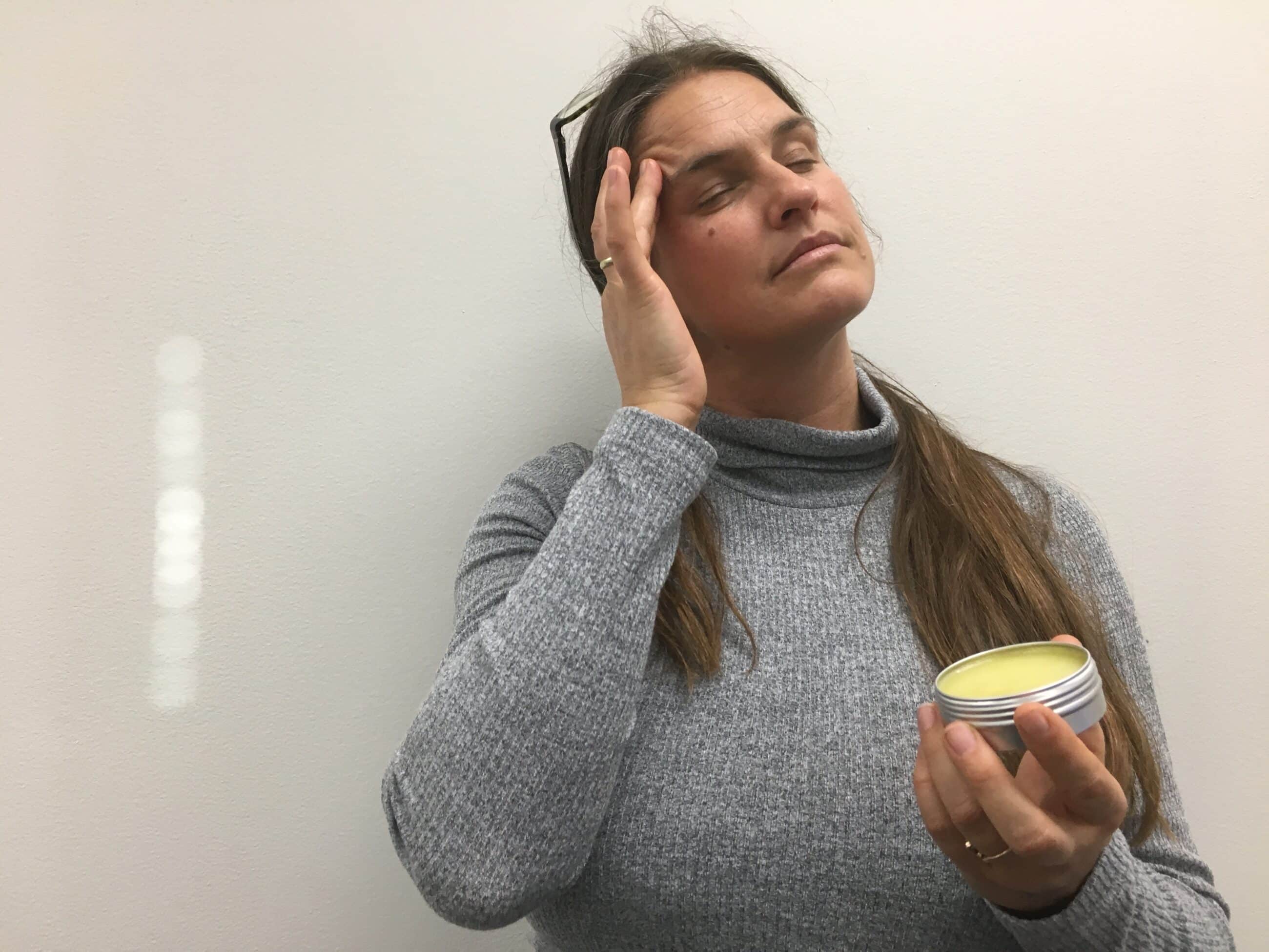 A woman applying Dr. Bronner's organic magic balm to her face