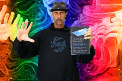 A man posing with the book, 'How to Change Your Mind' by Michael Pollan