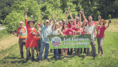 A group of activists celebrating while holding a banner that reads, 'Let Farmers Grow Hemp'